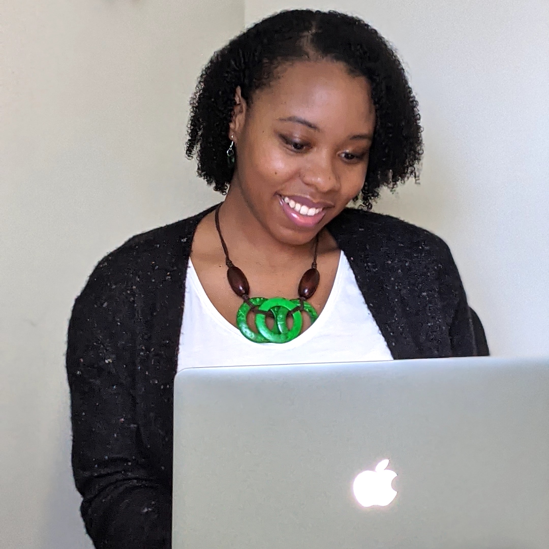 SEO Geneva Bell wearing a purple shirt and green necklace.