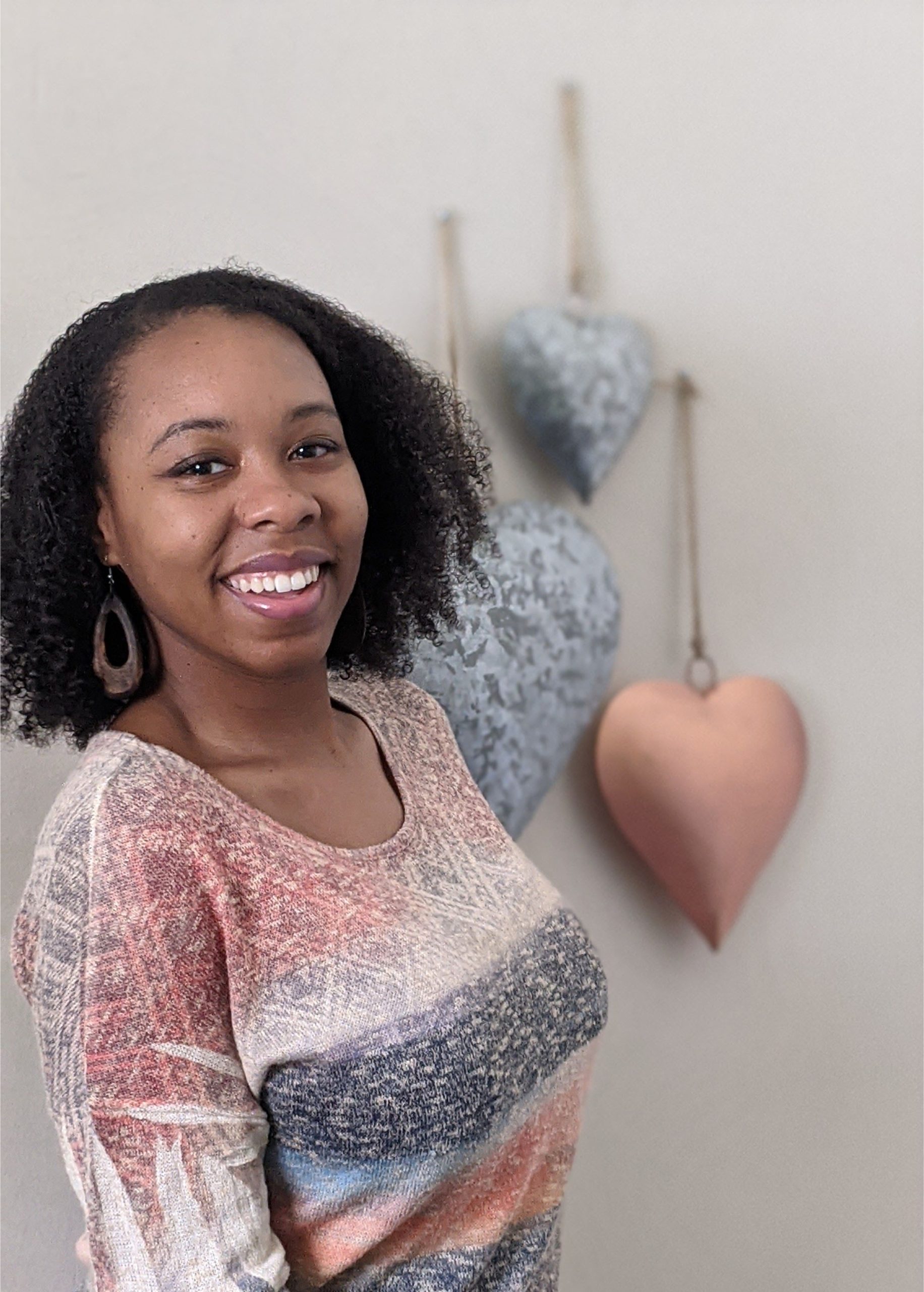 SEO agency owner Geneva Bell wearing a pink sweater with metal hearts in the background.